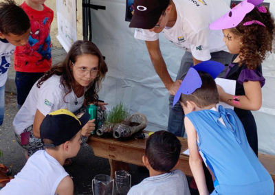 Equipe de Educação Ambiental realiza experimento para mostrar às crianças como a mesma situação, que simula água da chuva, produz diferentes realidades em área com vegetação e sem vegetação